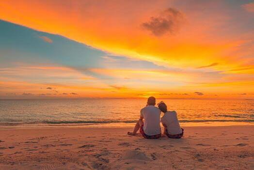 A romantic couple sitting on the beach watching a golden sunset during a Tanzania honeymoon safari