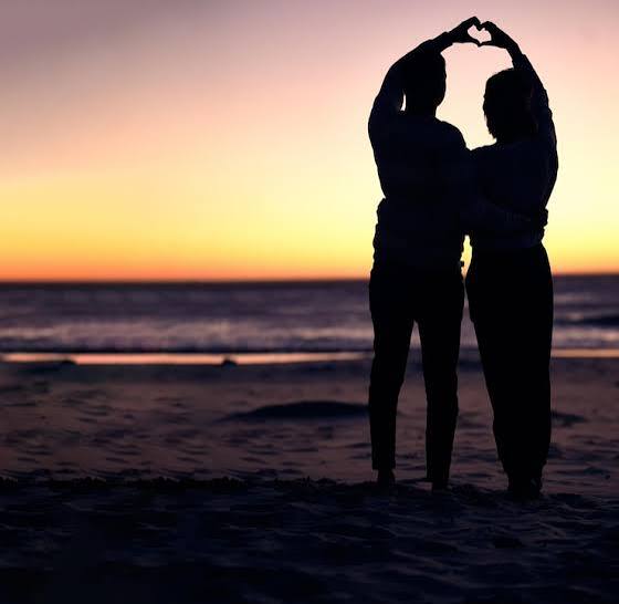 Silhouette of a romantic couple making a heart shape on the beach at sunset during a Tanzania honeymoon safari