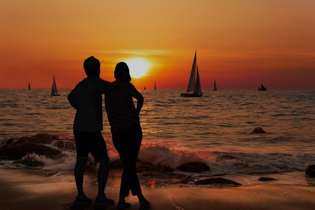 A romantic couple standing on a beach enjoying a sunset view during a honeymoon safari in Tanzania