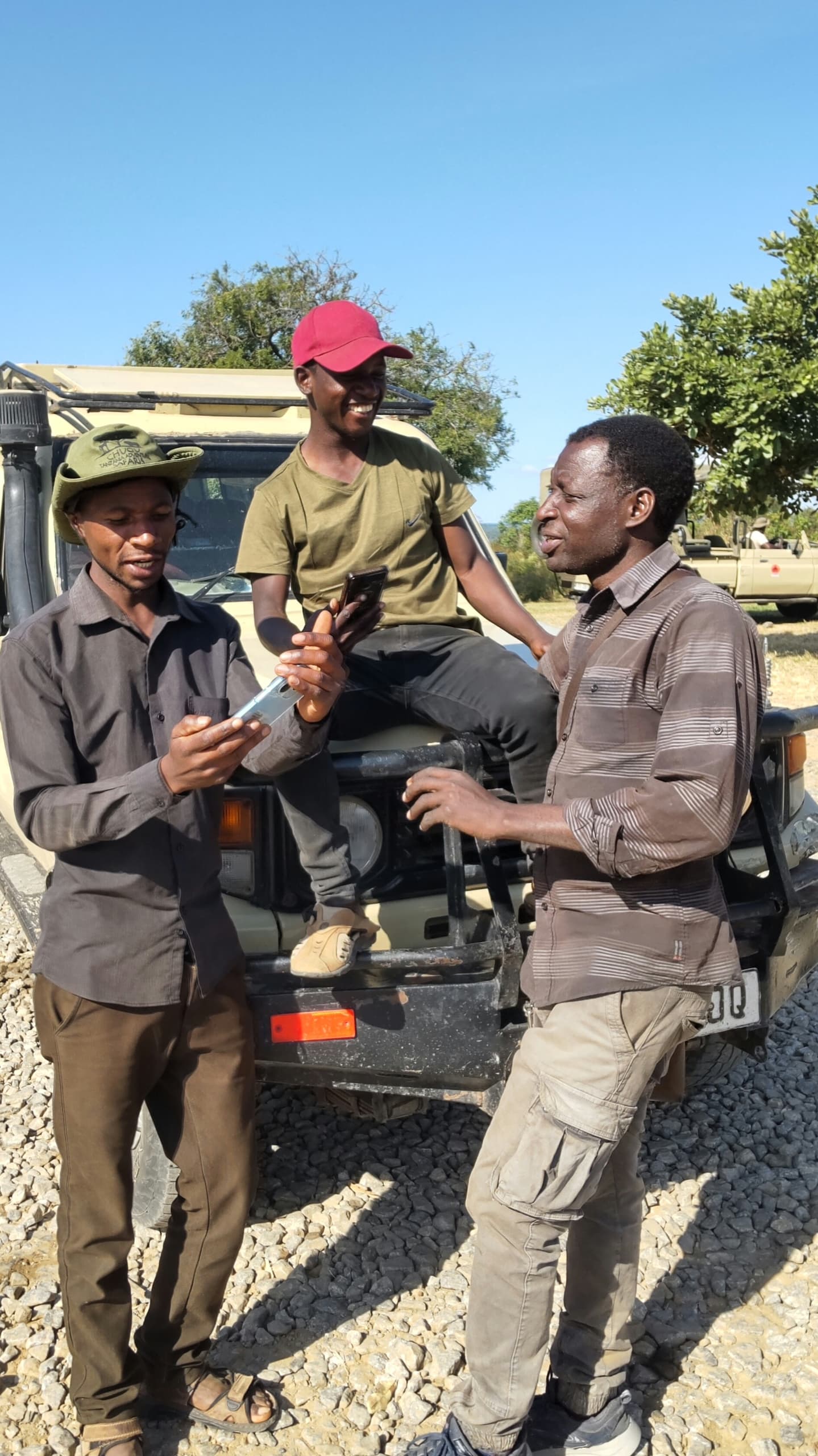 Local safari guides taking a break near a safari vehicles during a wildlife tour in Tanzania